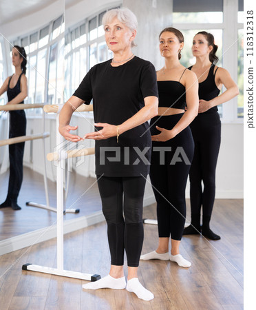 Girls in ballet class perform first position with participation of mature female mentor Girls in ballet class perform first position with participation of mature female mentor 118312318