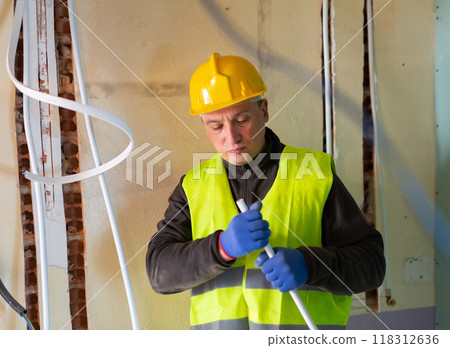 Plumber prepares plastic pipes for installation in building under construction Plumber prepares plastic pipes for installation in building under construction 118312636