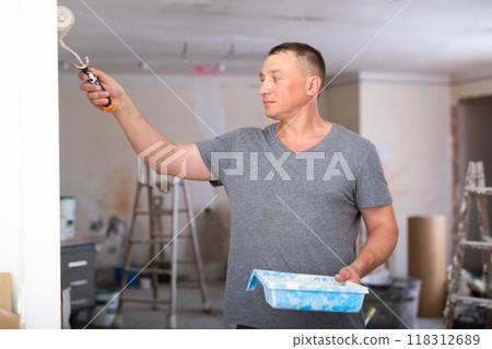 Portrait of positive man painter with paint roller Portrait of positive man painter with paint roller 118312689