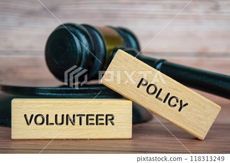 Volunteer policy text engraved on wooden blocks with gavel background. Volunteer policy concept Volunteer policy text engraved on wooden blocks with gavel background. Volunteer policy concept 118313249