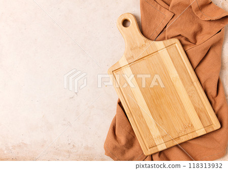 Cutting board, beige, unpainted, with a kitchen towel, on a beige background, top view, 118313932