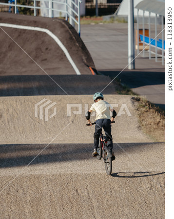 Boy or young rider on BMX Race made from soil and sand. Adrenaline-Pumping Dirt BMX Race Track. Extreme sport and bicycling concept 118313950