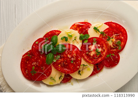 Caprese salad, Italian traditional dish, tomatoes with mozzarella cheese, basil and spices, top view, no people, Caprese salad, Italian traditional dish, tomatoes with mozzarella cheese, basil and spices, top view, no people, 118313990