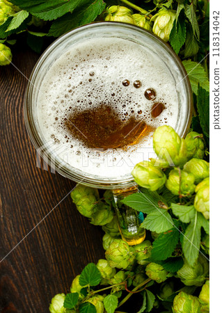 A mug of beer , on a wooden table, with a branch of fresh hops, rustic , no people, A mug of beer , on a wooden table, with a branch of fresh hops, rustic , no people, 118314042