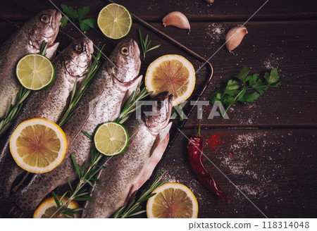 Raw rainbow trout, with lemon and herbs, on a wooden table, no people, 118314048