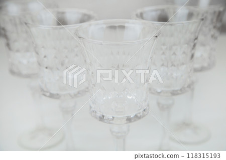 Crystal wine glasses with expanded edges and faceted pattern stand in a wedge on a white background close-up. High quality photo Crystal wine glasses with expanded edges and faceted pattern stand in a wedge on a white background close-up. High quality photo 118315193