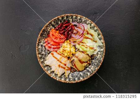 Healthy quinoa bowl with chicken, vegetables, beans, and dressing for a nutritious and balanced meal 118315295