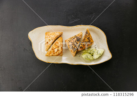 Freshly baked artisan bread slices with almonds and seeds, served with herbed butter on a plate 118315296
