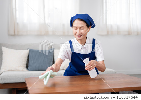 Senior female housekeeper in a white polo shirt with a blue apron 118317644
