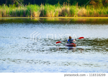 Woman is paddling in a kayak in the forest lake in summer. Woman is paddling in a kayak in the forest lake in summer. 118318209