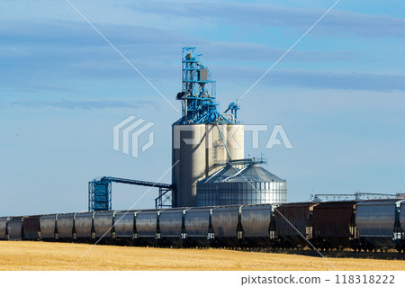 Rural scene in prairies - grain elevator and new train cars on the railway tracks in the autumn field under the blue sky. Rural scene in prairies - grain elevator and new train cars on the railway tracks in the autumn field under the blue sky. 118318222