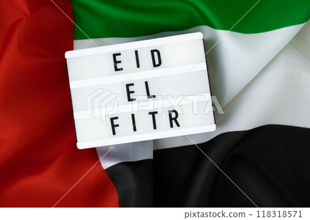 EID EL FITR - Eid Mubarak - Happy Holidays text frame on United Arab Emirates waving flag made from silk material. Public holiday celebration background. The National Flag of UAE. Commemoration Day EID EL FITR - Eid Mubarak - Happy Holidays text frame on United Arab Emirates waving flag made from silk material. Public holiday celebration background. The National Flag of UAE. Commemoration Day 118318571