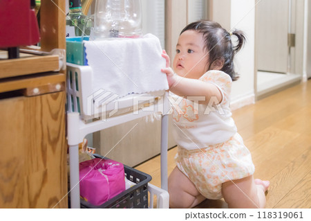 [Baby with twin tails standing up in the kitchen] 118319061