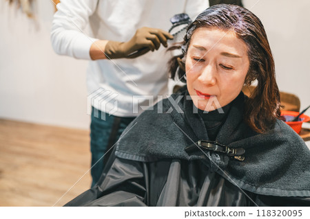 A woman in her 50s having her hair dyed gray at a beauty salon 118320095