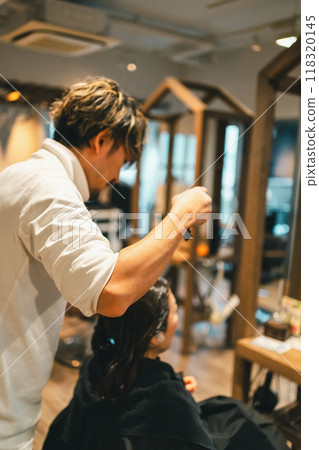 A male hairdresser and an adult woman doing gray hair coloring at a beauty salon 118320145