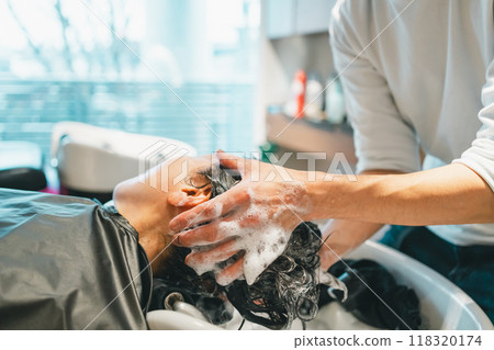 Adult woman and male hairdresser being shampooed at the shampooing station in a beauty salon 118320174