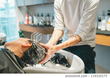 Adult woman and male hairdresser being shampooed at the shampooing station in a beauty salon 118320175