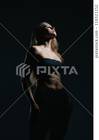 Model striking a pose in dramatic lighting against a dark background 118321152