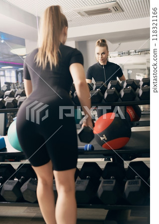 Woman lifting weights in a gym with a focus on fitness and health Woman lifting weights in a gym with a focus on fitness and health 118321166