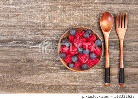 Mix of blueberries and raspberries in a plate with wooden fork and spoon. 118321622