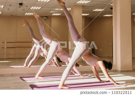Well looking middle aged sporty woman, fitness instructor in pink sportswear doing stretching and pilates on yoga mat in the studio with mirror. Female fitness yoga. Healthy lifestyle and harmony. 118322811