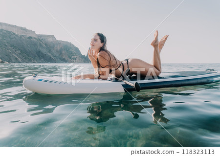 Woman Paddleboarding Seascape Summer - Young woman laying on paddleboard in the ocean during summer. Woman Paddleboarding Seascape Summer - Young woman laying on paddleboard in the ocean during summer. 118323113