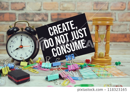 Create, Do Not Just Consume text on paper card with alarm clock and stationary on wooden background 118323165