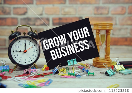 Grow Your Business text on paper card with alarm clock and stationary on wooden background Grow Your Business text on paper card with alarm clock and stationary on wooden background 118323218