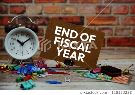 End of Fiscal Year text on paper card with alarm clock and stationary on wooden background 118323228