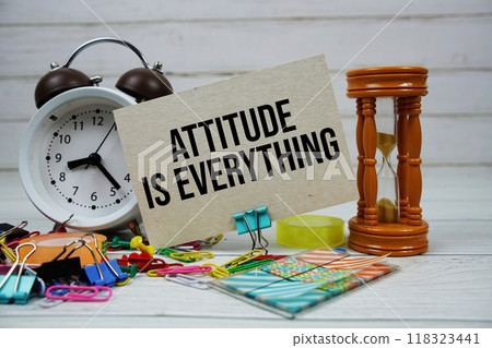 Attitude Is Everything text on paper card with alarm clock and stationary on wooden background 118323441
