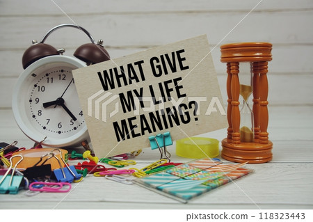 What Gives My Life Meaning? text on paper card with alarm clock and stationary on wooden background 118323443