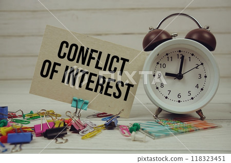 Conflict Of Interest text on paper card with alarm clock and stationary on wooden background 118323451
