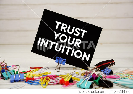 Trust Your Intuition text on paper card with stationary on wooden background Trust Your Intuition text on paper card with stationary on wooden background 118323454