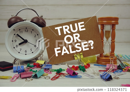True or False text on paper card with alarm clock and stationary on wooden background 118324371