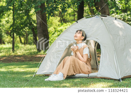 在露營地/休閒設施的帳篷前喝飲料的女孩 在露營地/休閒設施的帳篷前喝飲料的女孩 118324421