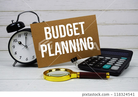 Budget Planning text on paper card with alarm clock, calculator and magnifying glass on wooden background Budget Planning text on paper card with alarm clock, calculator and magnifying glass on wooden background 118324541