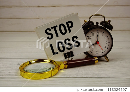 Stop Loss text on paper card with alarm clock and magnifying glass on wooden background Stop Loss text on paper card with alarm clock and magnifying glass on wooden background 118324597