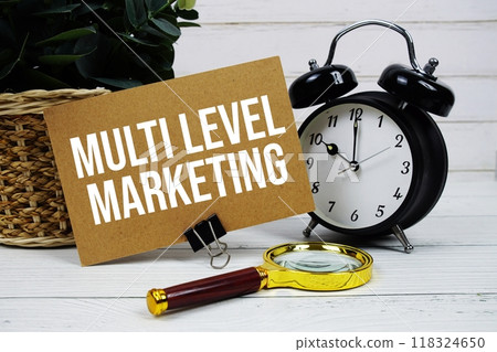 Multi Level Marketing text on paper card with alarm clock and magnifying glass on wooden background Multi Level Marketing text on paper card with alarm clock and magnifying glass on wooden background 118324650