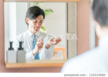 Young Asian businessman in a suit applying perfume to his wrist before going to work in the morning (men's cologne, men's perfume) Young Asian businessman in a suit applying perfume to his wrist before going to work in the morning (men's cologne, men's perfume) 118324980