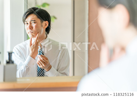 Young Asian businessman in a suit shaving in the bathroom before going to work in the morning Young Asian businessman in a suit shaving in the bathroom before going to work in the morning 118325116
