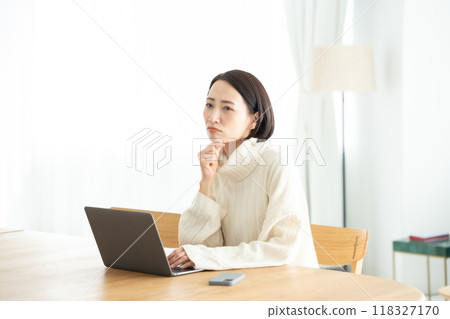 一位在客廳操作電腦的女士很擔心 118327170