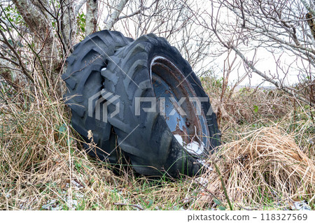Concept of environmental pollution with old tractor tyres and wheels in the forest 118327569