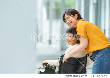 Senior woman in a wheelchair and young woman caring for her Senior woman in a wheelchair and young woman caring for her 118327644