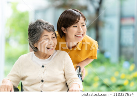一名坐在輪椅上的老年婦女和一名照顧她的年輕婦女 一名坐在輪椅上的老年婦女和一名照顧她的年輕婦女 118327654