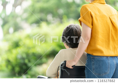 Senior woman in a wheelchair and young woman caring for her, rear view Senior woman in a wheelchair and young woman caring for her, rear view 118327882