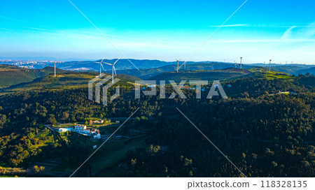 Wind farm generating green energy. Wind turbines with blades in field aerial view. Alternative energy. Scenic Aerial view of wind turbines farm over green beautiful landscape. 118328135
