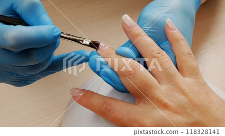 Manicurist paints nails with  gel polish. Application of acrylic polish on nails.   Application Shellac on nails.  Manicure service.  Specialist covers the nail of client by clear gel. Close up. 118328141