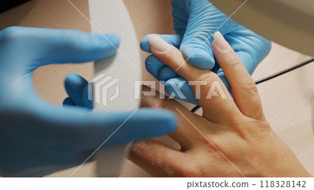 Nail care at home. Process of nail treatment in a nail salon. A view from behind the nail master shoulder of the nail care process. 118328142