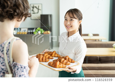 A young female sales clerk recommending a croissant A young female sales clerk recommending a croissant 118328359