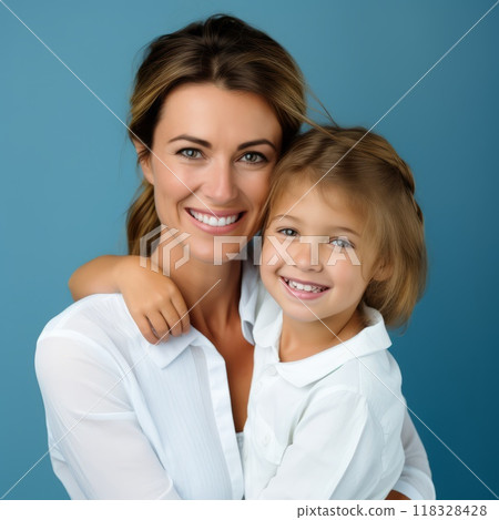 Happy mother and child in white shirts standing on a blue background. Smiling mother hugging her daughter. Closeup studio portrait of caucasian mom and her child smiling with shiny white teeth. 118328428